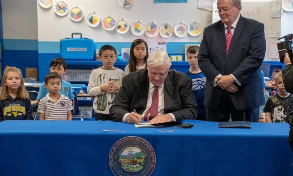 Governor Jim Justice signs paper at a classroom