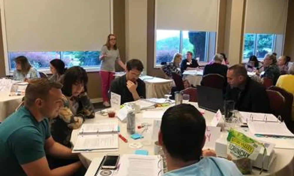 Educators sitting around a table at a National Board Certification training hosted by the WV Department of Education