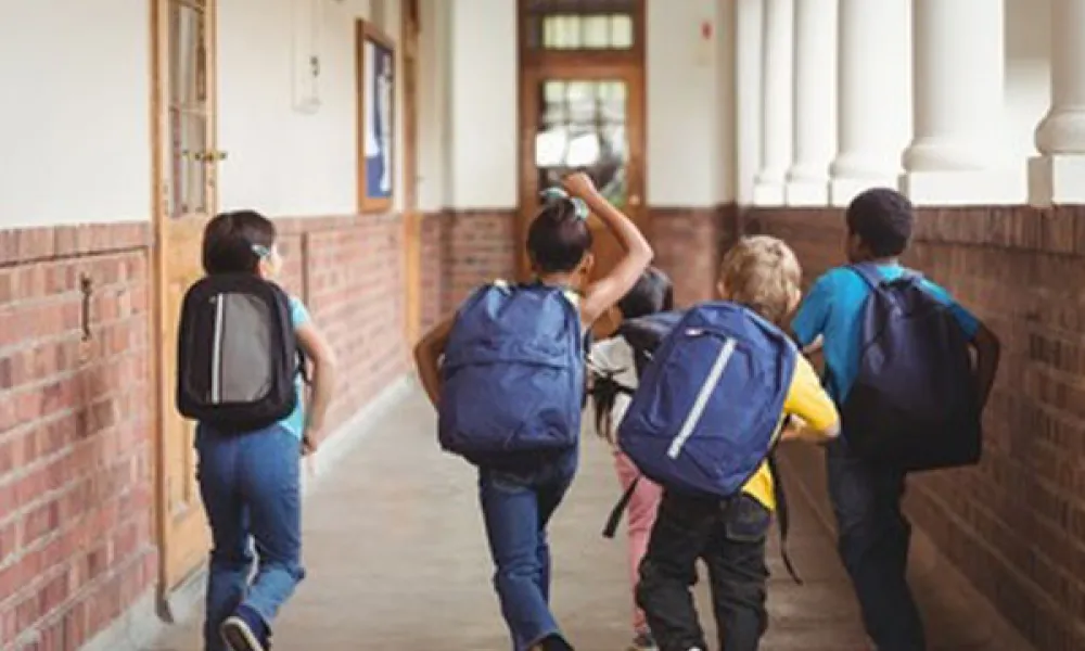 Five elementary students walking down the hallway