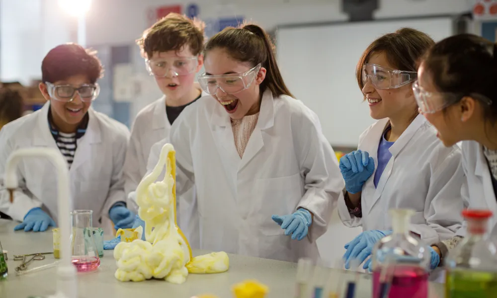 Students dressed in laboratory protective equipment watching an experiment with expanding foam