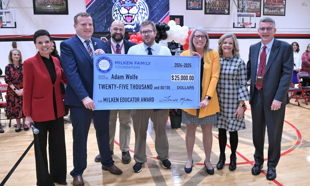 Milken winner holds a check