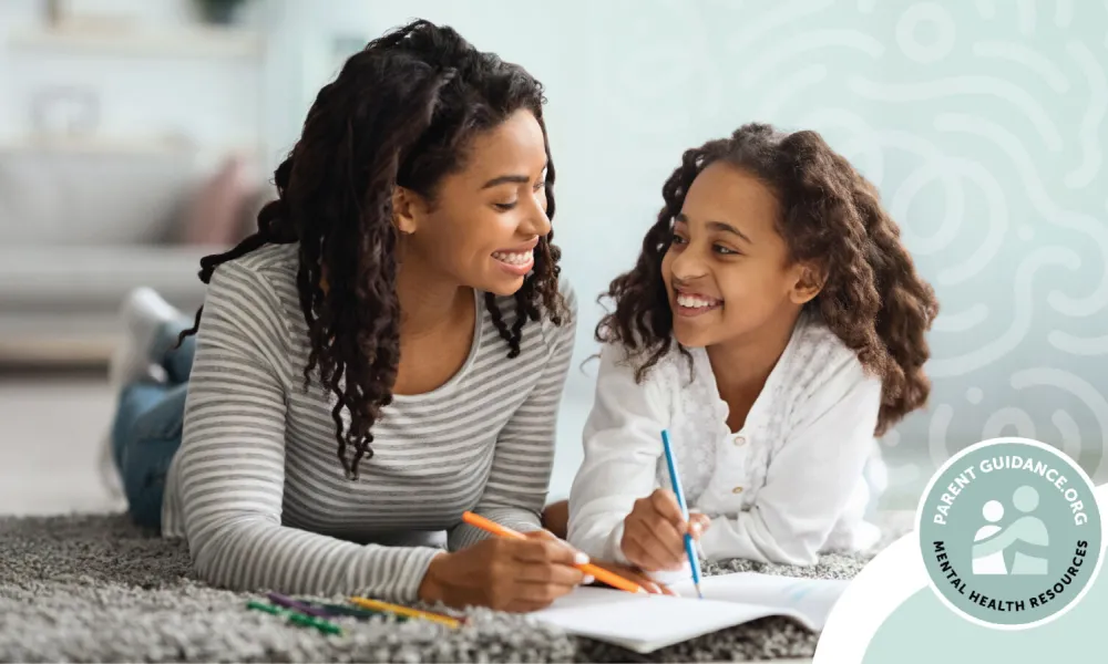 A mother and daughter are lying on the floor, smiling and drawing together. The mother is wearing a striped shirt, while the daughter is in a white top. Both have curly hair and appear happy and engaged in their activity. In the bottom right corner, there is a logo that reads "Parent Guidance.org Mental Health Resources." The background features a softly patterned wall.