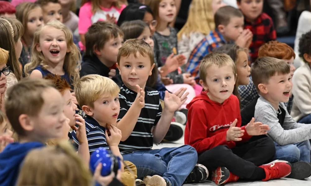 Children gather on the floor for a school assembly.