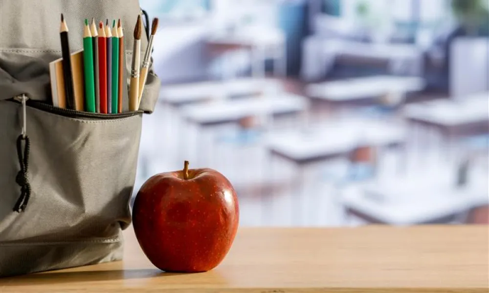 An apple sits on top of a teacher's desk.