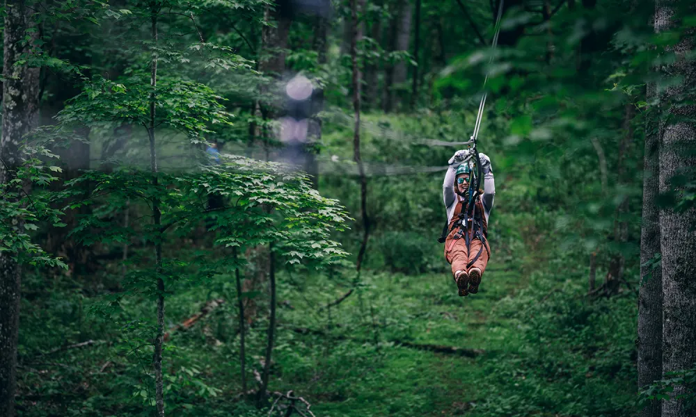 A young woman zip-lining through Pipestem National Forest