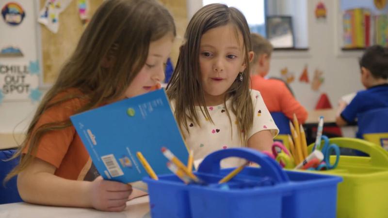 Two elementary students looking through a book together.