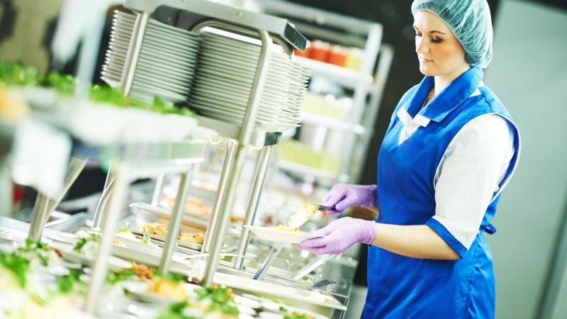 buffet female worker preparing and servicing food in cafeteria