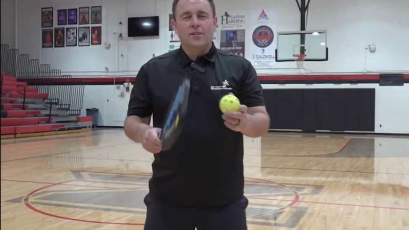 Instructor holding tennis racket and tennis ball.