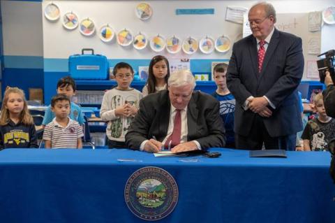 Governor Jim Justice signs paper at a classroom