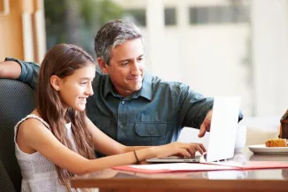 Father helping his daughter with laptop