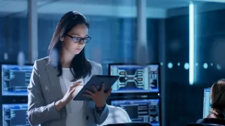 Young Female Employee using a tablet, surrounded by computer equipment.