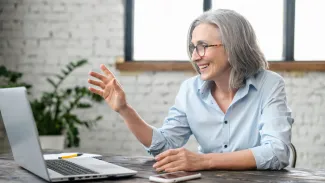 Woman waves at laptop.