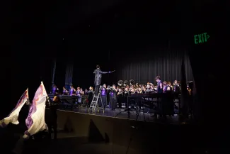 Members of a marching band performing on a stage.