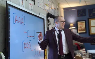 Teacher pointing to classroom and holding a smart board pen.