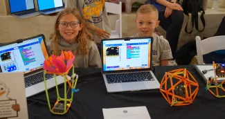 Students sitting at a table behind computers.