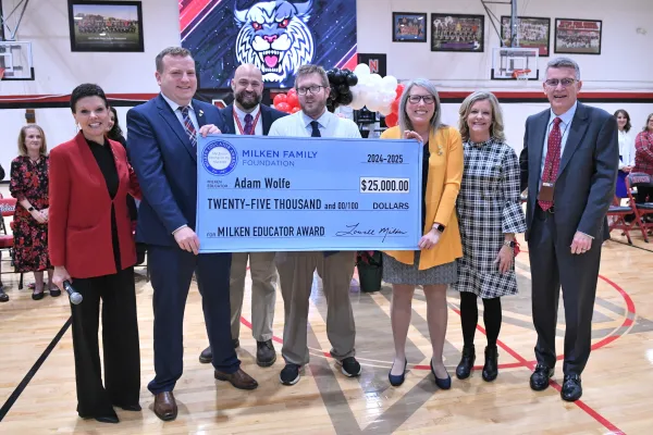 Milken winner holds a check