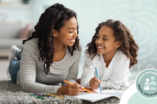 A mother and daughter are lying on the floor, smiling and drawing together.